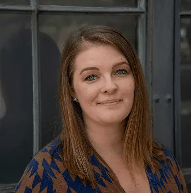 A heashot photo of our team member Dr. Mary Robins, smiling in a navy and brown shirt.